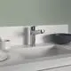 Küchenarbeitsplatte mit einer Chrom-Armatur von Ideal Standard und einem Handbrausekopf, daneben ein schwarzer Schüssel und weiße Teller.